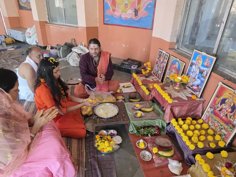 A family seated before the deities as the puja begins